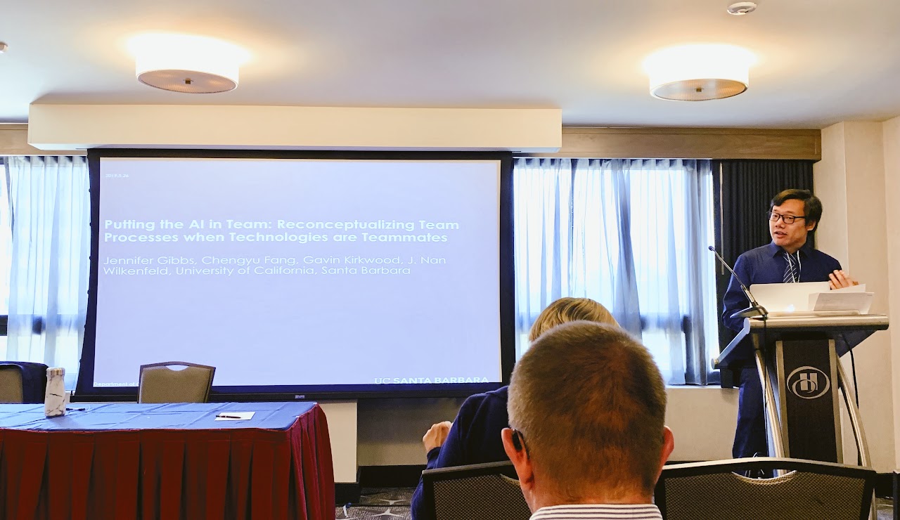 Chengyu Fang speaking beside a slide titled Putting the AI in Team at a 2019 research presentation